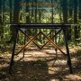 Schwarzer Aluminium Campingtisch mit orange hervorgehobener Kreuzstruktur für Stabilität im Wald. Klappbar.