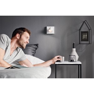 Weißer Philips myLiving LED-Spot Star an grauer Wand über Nachttisch im Schlafzimmer.