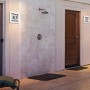 Quadratische LED Hausnummernleuchte Alice mit Ziffernaufklebern an Hauswand.