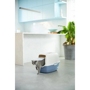 Rotho Katzentoilette Bailey Horizontblau/Sand. Katze tritt aus dem Katzenklo mit Haube und Schwingtür in moderner Umgebung.