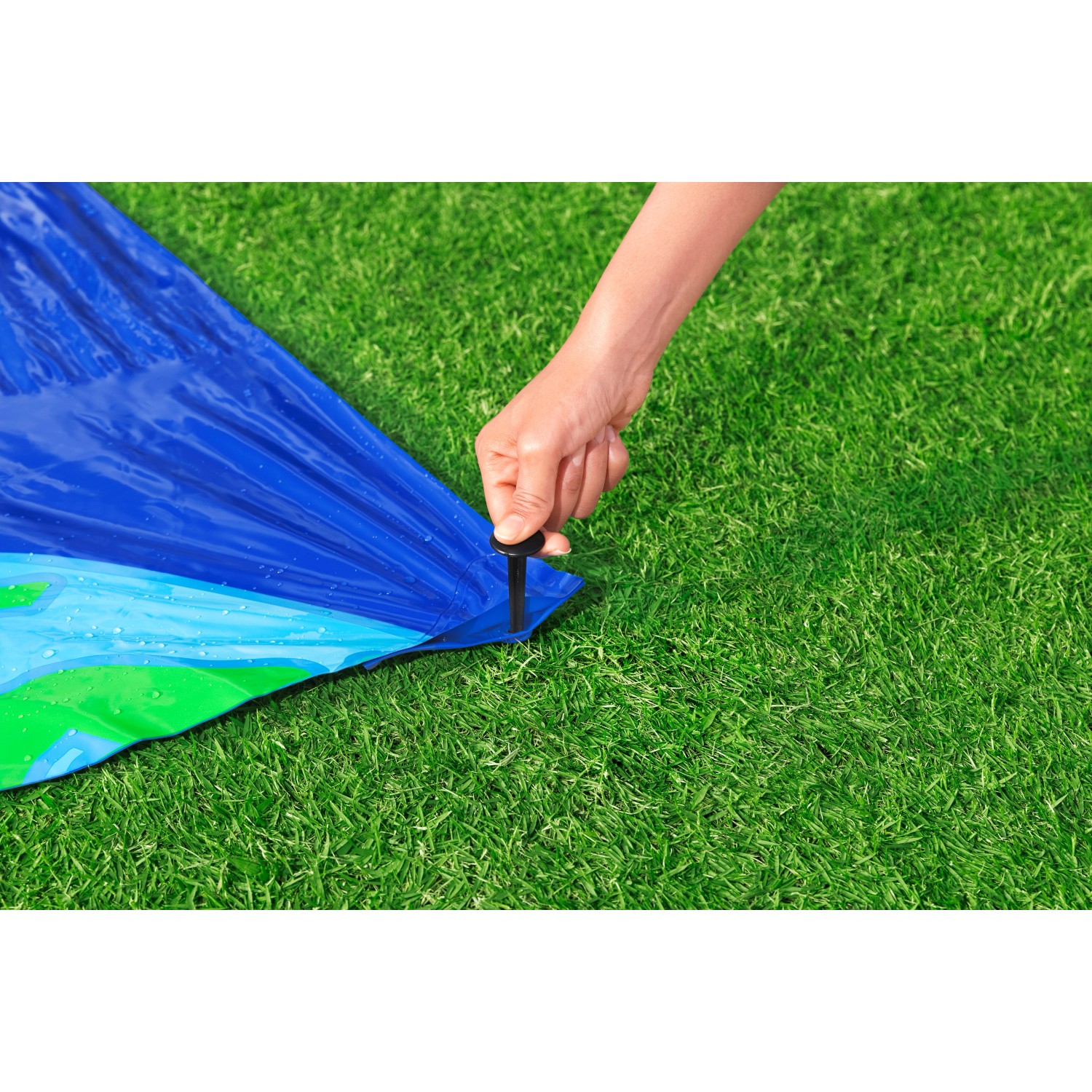 Detailaufnahme: Bestway Wasserrutsche wird mit Hering im Rasen fixiert.