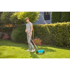 Mann nutzt Gardena Combisystem Streuwagen im Garten zur Rasenpflege.