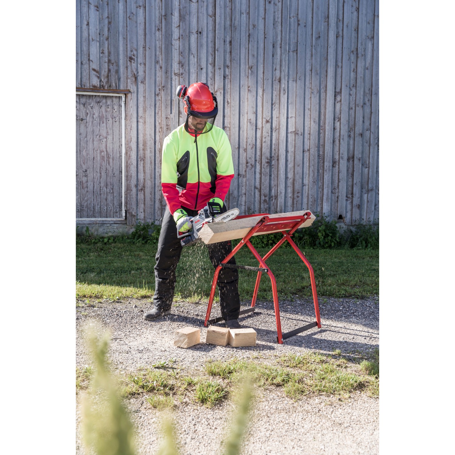Al-Ko Akku-Kettensäge CS 1825 beim Sägen von Holz auf einem Sägebock, mit Schutzkleidung.