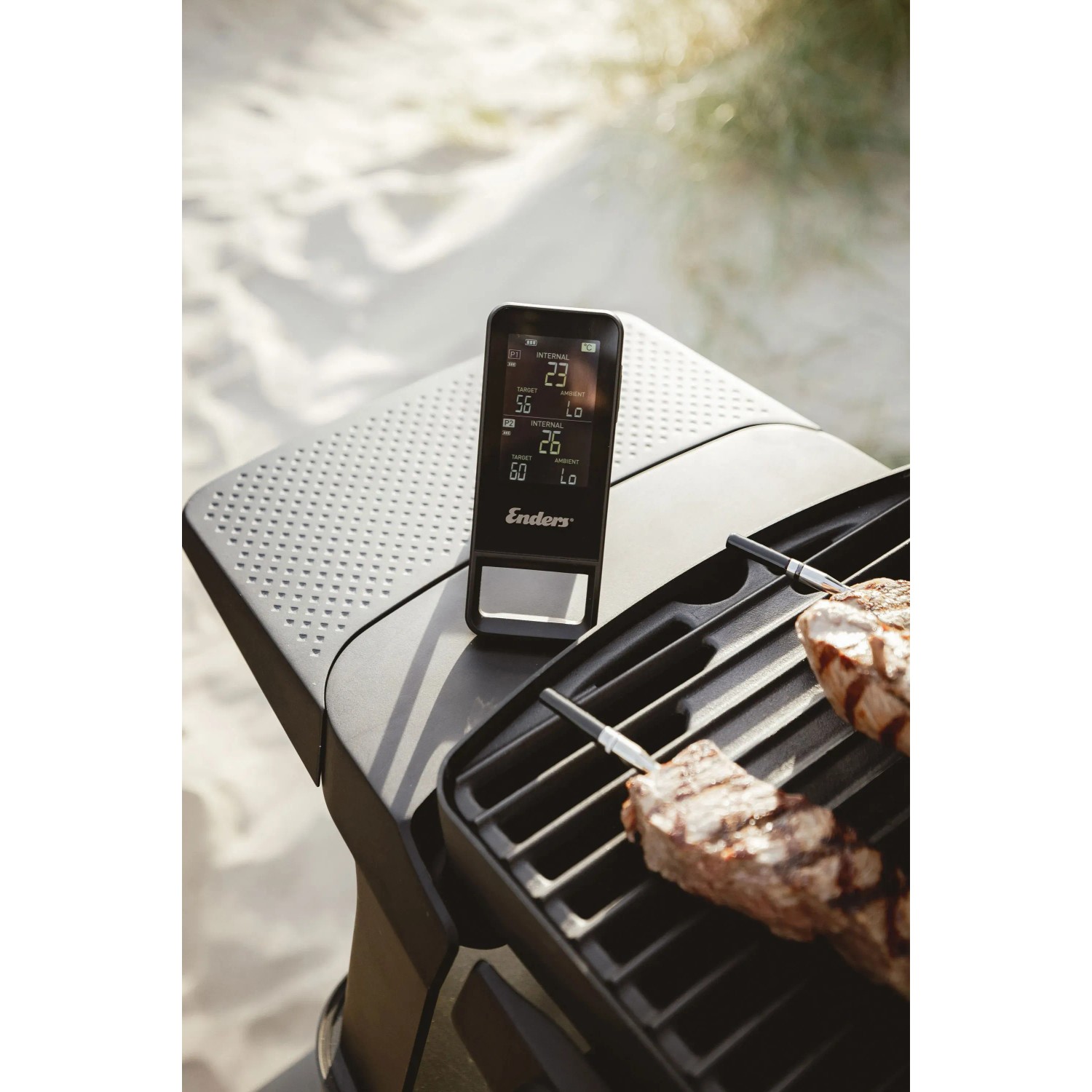 Enders Celsio II Bluetooth Thermometer mit zwei Fühlern und Grillgut auf einem Grill.
