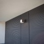 Moderne Lutec LED-Außenwandleuchte Cuba in Anthrazit mit warmweißem Licht an einer Fassade.