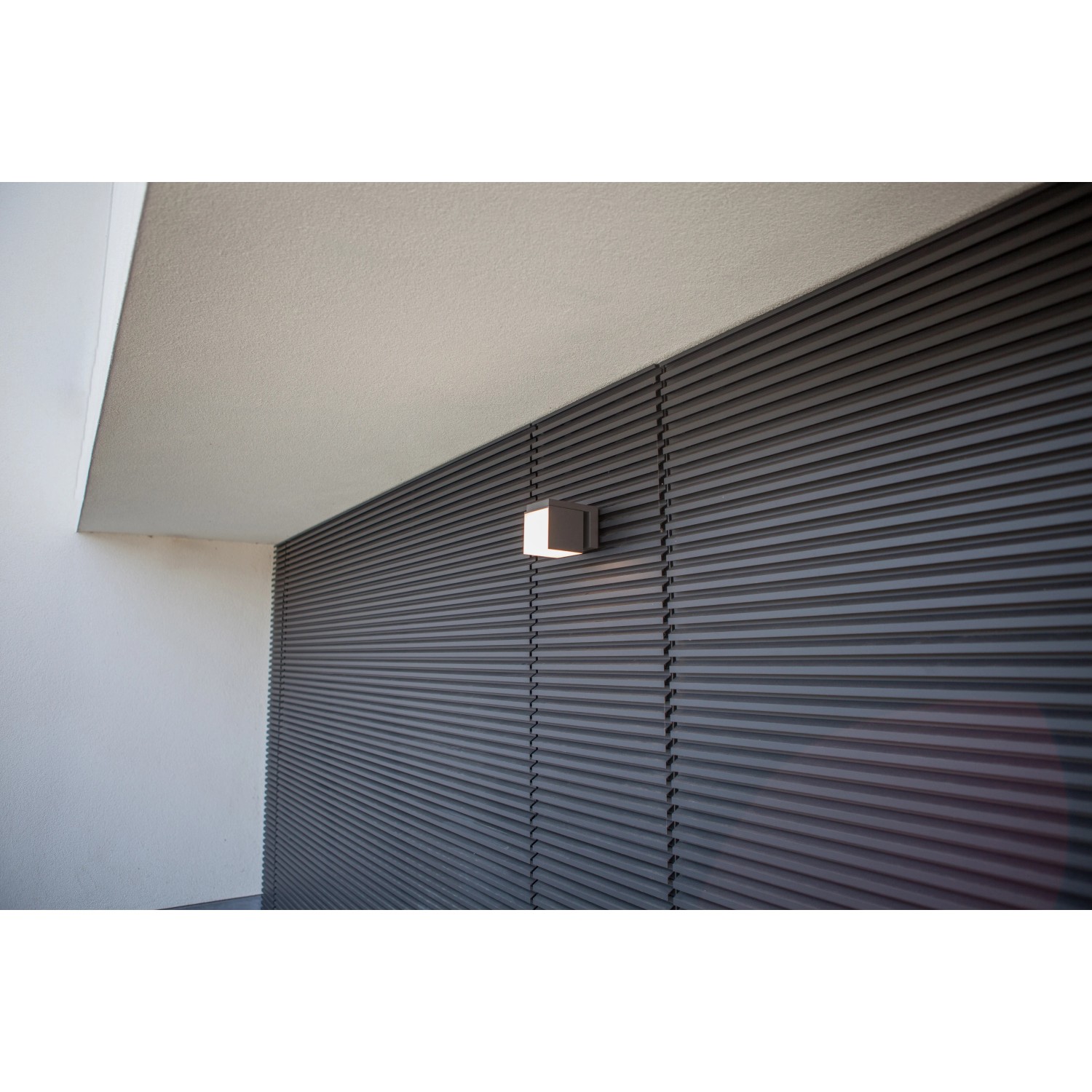 Moderne Lutec LED-Außenwandleuchte Cuba in Anthrazit mit warmweißem Licht an einer Fassade.