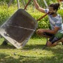 Mann reinigt Schubkarre mit Wasserstrahl im Garten. Gardena Haus- und Gartenautomat 5000 Silent Comfort.