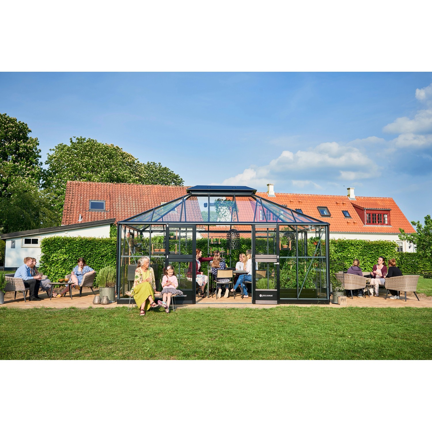 Großes, anthrazitfarbenes Juliana Gewächshaus Grand Oase 18 mit Personen im Garten.