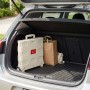 Beiger, klappbarer Relaxdays Einkaufstrolley aus Kunststoff im Kofferraum, neben Einkaufstaschen. Praktischer Transporthelfer.