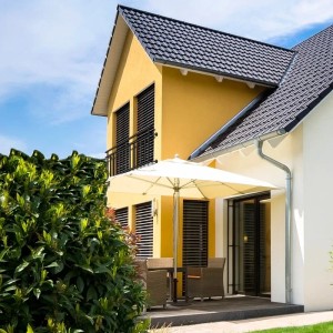 Schwarzer ECD Germany Französischer Balkon (184x90 cm) am gelben Haus mit Terrassenmöbeln.