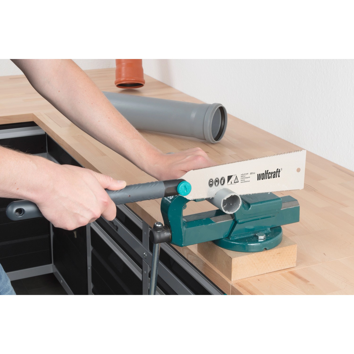 Wolfcraft Japansäge 240 mm beim Sägen eines Rohrs im Schraubstock. Handsäge mit grauem Griff.