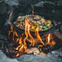 Petromax Dutch Oven Set FT9-T-Scrub: Gusseisen-Topf mit Gemüse über offenem Feuer. Ideal zum Kochen im Freien.