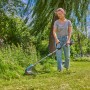 Frau trimmt Rasen mit Gardena Akku-Rasentrimmer PowerTrim 30/18V. Akku-Trimmer im Einsatz.