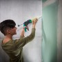 Frau benutzt wolfcraft Kartuschenpresse MG 310 Compact zum Verfugen einer Wand.