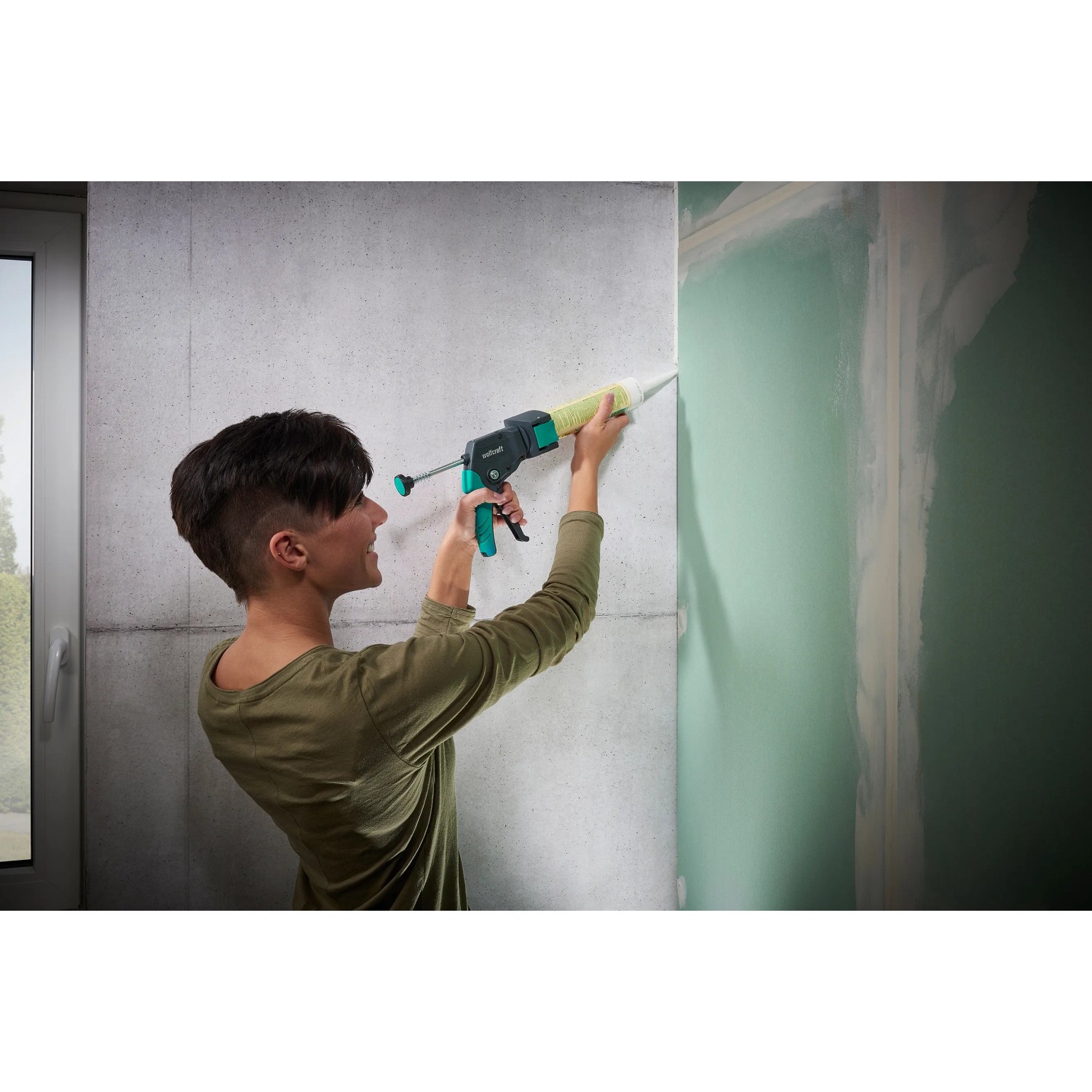 Frau benutzt wolfcraft Kartuschenpresse MG 310 Compact zum Verfugen einer Wand.