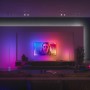 Weiße Philips Hue Gradient Signe Stehleuchte im Wohnzimmer mit Farbverlauf an der Wand.