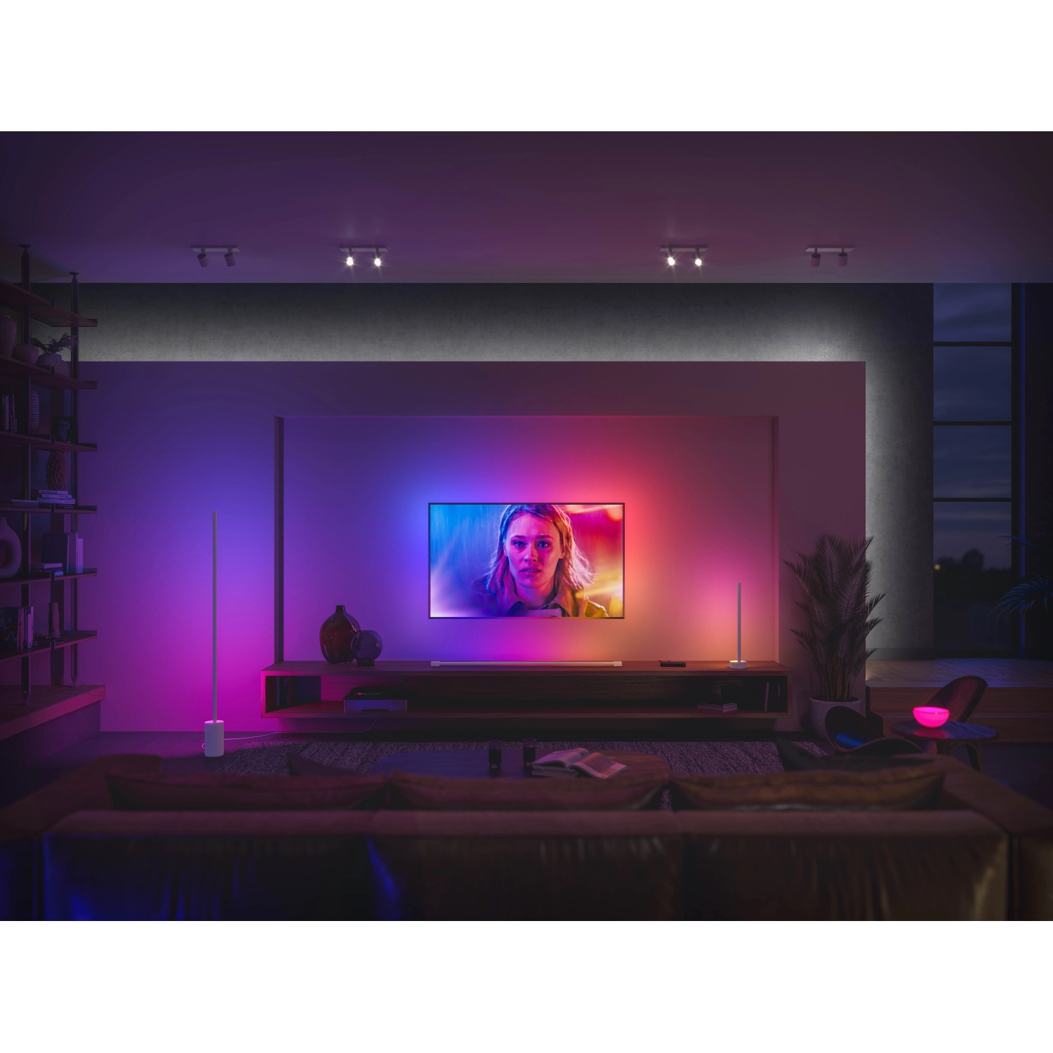 Weiße Philips Hue Gradient Signe Stehleuchte im Wohnzimmer mit Farbverlauf an der Wand.