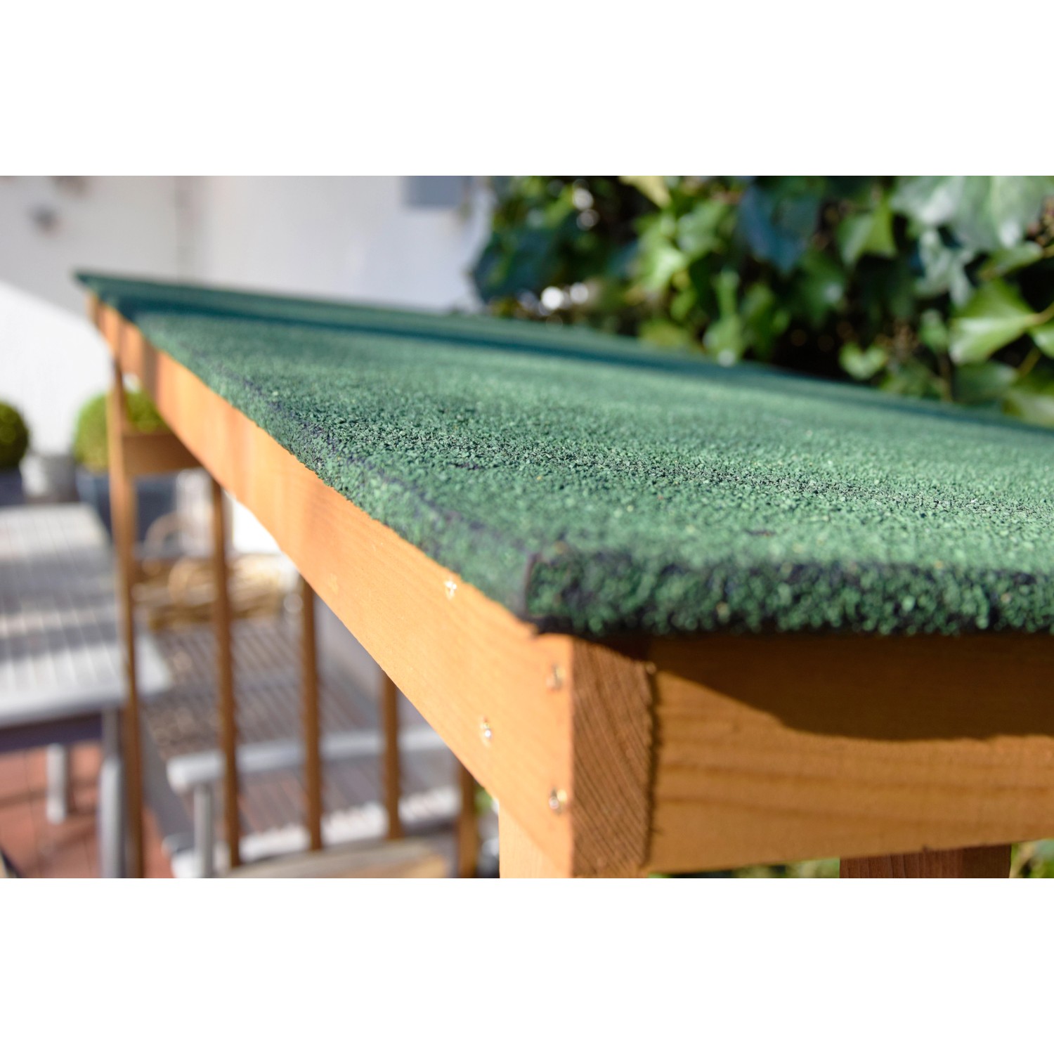 Detailaufnahme: Grünes Bitumendach des Dobar Kaminholzregals aus Kiefernholz.