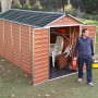 Palram Canopia Gerätehaus Skylight 185x379cm Amber mit geöffneten Türen und Mann davor.