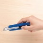 Hand hält blaues LUX Cuttermesser Classic 100 mm vor hellem Holzgrund.