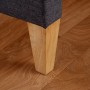 Detailaufnahme: Graues Polsterbett (90x200) mit Holzfuß auf Holzboden.