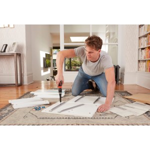 Mann montiert Möbel mit Black+Decker Akkuschrauber BCF601C im Wohnzimmer.