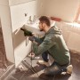 Mann bohrt mit Bosch EasyImpact 600 Schlagbohrmaschine in Fliese im Bad.