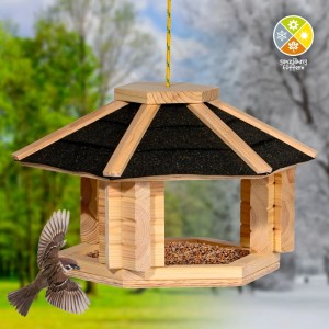 Dobar Vogelhaus Zwart aus hellem Kiefernholz mit schwarzem Bitumendach. Ein Spatz fliegt zum Futterhaus für Wildvögel.