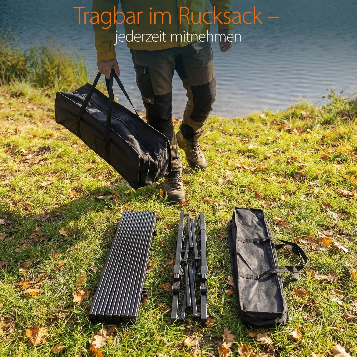 Person trägt Tragetasche mit Campingtisch am See. Zerlegter Aluminium Klapptisch und Tasche liegen auf Gras.