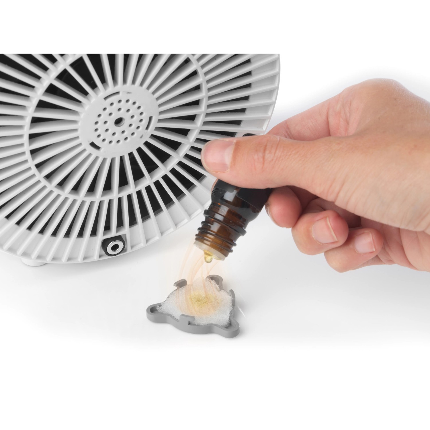 Beldray Standventilator: Hand träufelt Duftöl auf Aromakissen. Weißer Ventilator im Hintergrund.