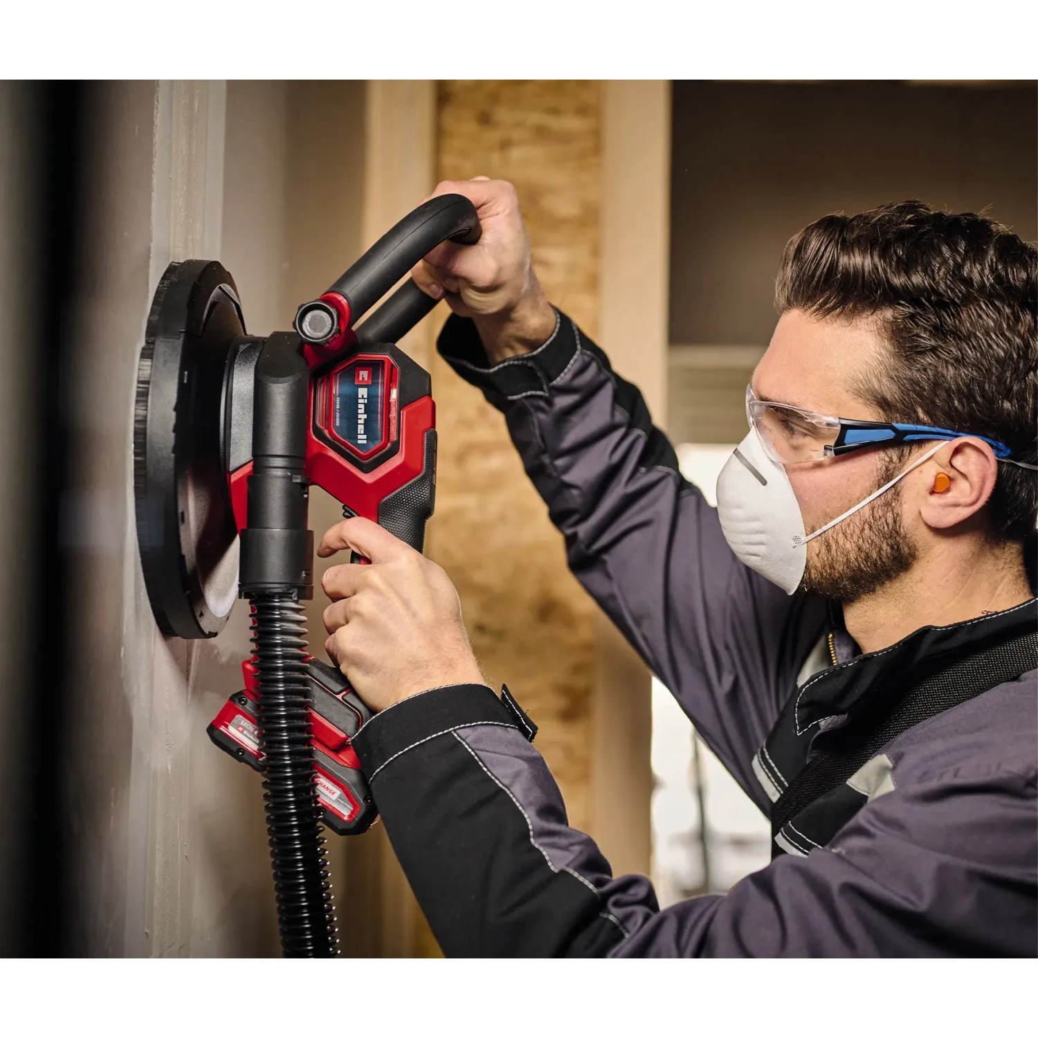 Einhell Akku-Trockenbauschleifer TP-DWS 18/225 im Einsatz beim Schleifen einer Wand. Staubabsaugung sichtbar.