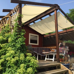 Peddy Shield Sonnensegel, 270x140 cm, Elfenbein, montiert über einer Terrasse mit Gartenmöbeln.