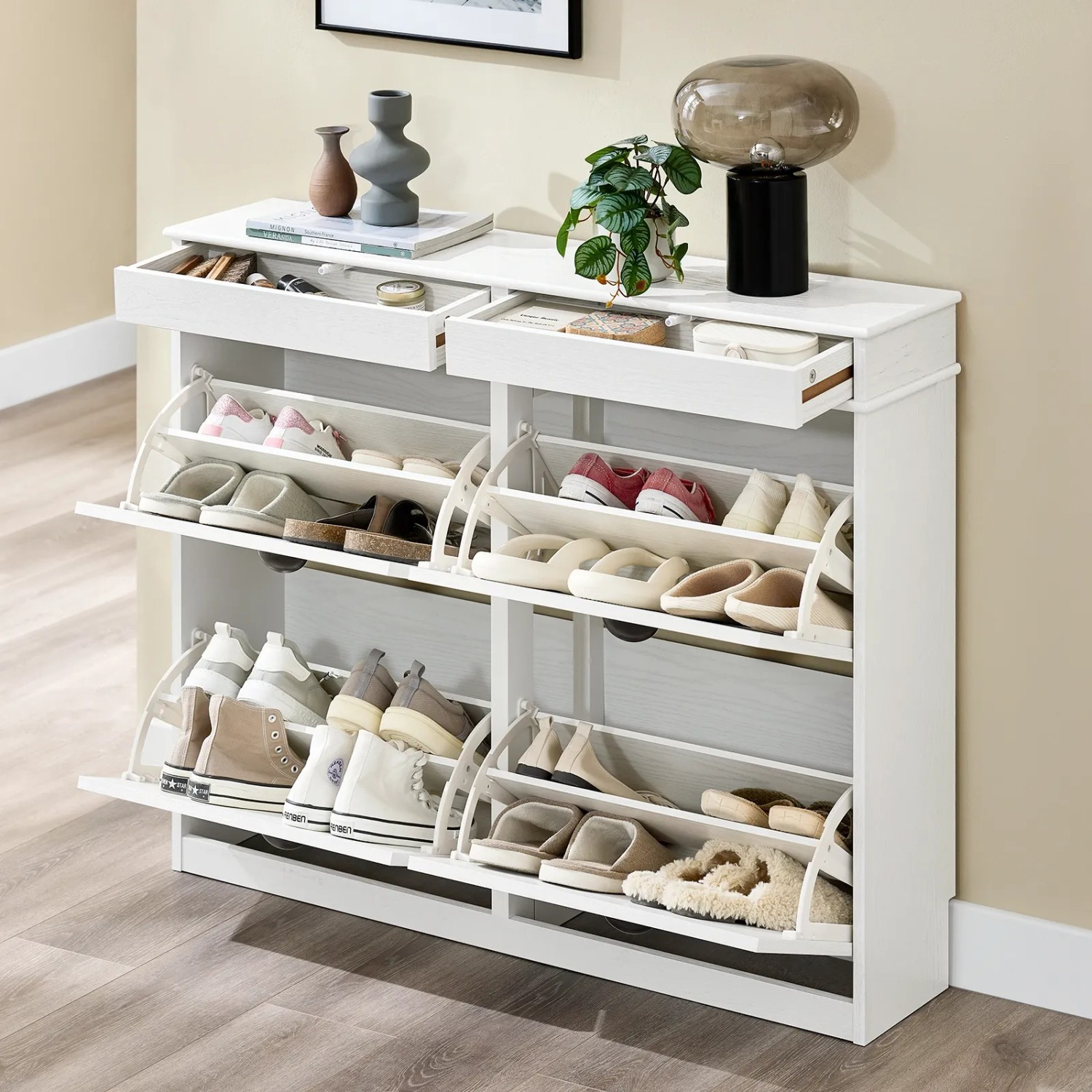 Weißer schmaler Schuhschrank mit 4 Klappen und 2 Schubladen, gefüllt mit Schuhen, im Flur. Ideal für die Diele.