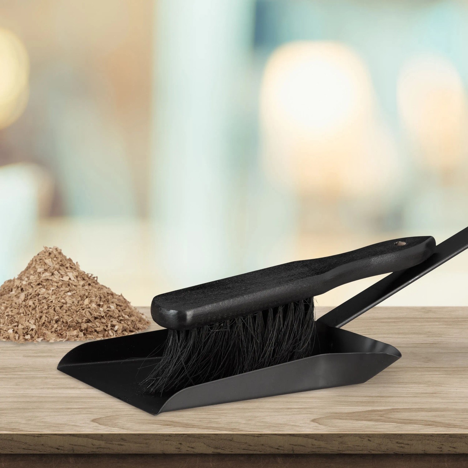 Schwarze Kehrgarnitur aus Stahl mit Holz-Handfeger auf Holztisch. Praktisches Reinigungsset für Haushalt, Kamin, Werkstatt.