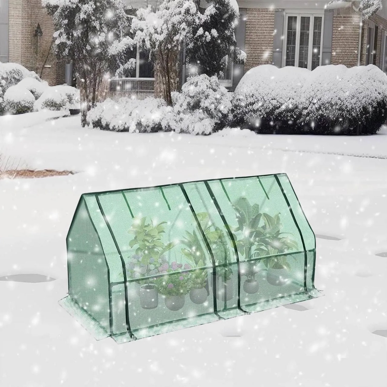 Grünes Foliengewächshaus mit Metallrahmen und Pflanzen im verschneiten Garten. Bietet Schutz vor Kälte und Frost.