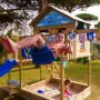 Blauer Wickey Disney Spielturm mit Rutsche und Schaukel, Kind schaukelt, Sandkasten im Garten.