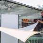 Ecru-farbenes, dreieckiges Siena Garden Sonnensegel Solino (3,6x3,6x3,6 m) wird montiert.