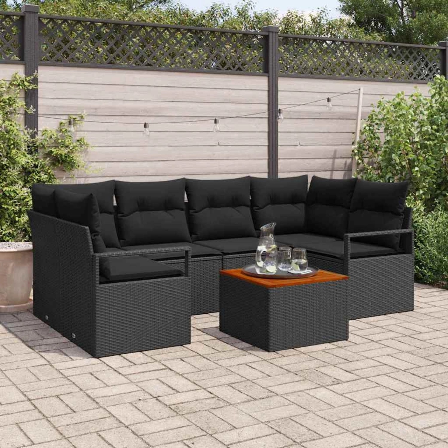 Schwarzes 7-teiliges Garten-Sofa-Set aus Poly Rattan mit Tisch und Kissen.