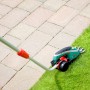 Bosch Isio Akku-Grasschere mit Teleskopstiel im Einsatz zum Rasenkantenschneiden.