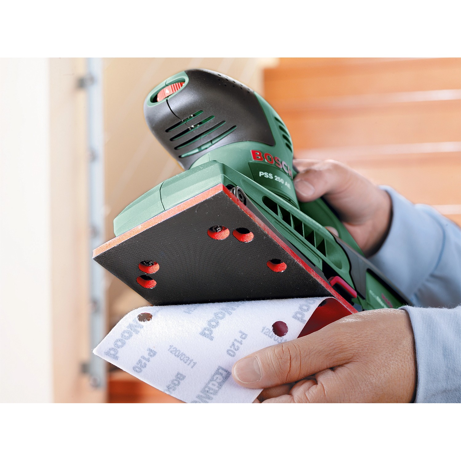 Bosch Schwingschleifer PSS 250 AE mit Schleifpapier in der Hand, Detailaufnahme.