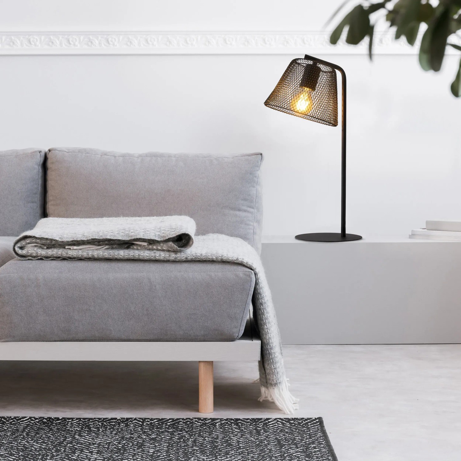 Schwarze Näve Tischleuchte Korie, 50 cm hoch, im Industrial Style neben einem grauen Sofa.