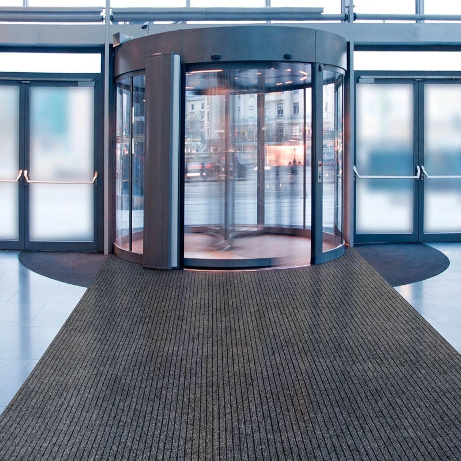 Grauer KARAT Eventteppich Atlas vor Drehtür, pflegeleichter Teppich nach Maß.