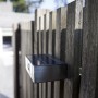 Moderne Lutec LED Solar-Wandleuchte Brick aus Edelstahl an Holzzaun, eckig, mit Bewegungsmelder.