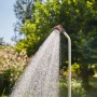 Gardena Gartendusche Solo im Einsatz: Wasserstrahl aus Duschkopf vor grünem Hintergrund.