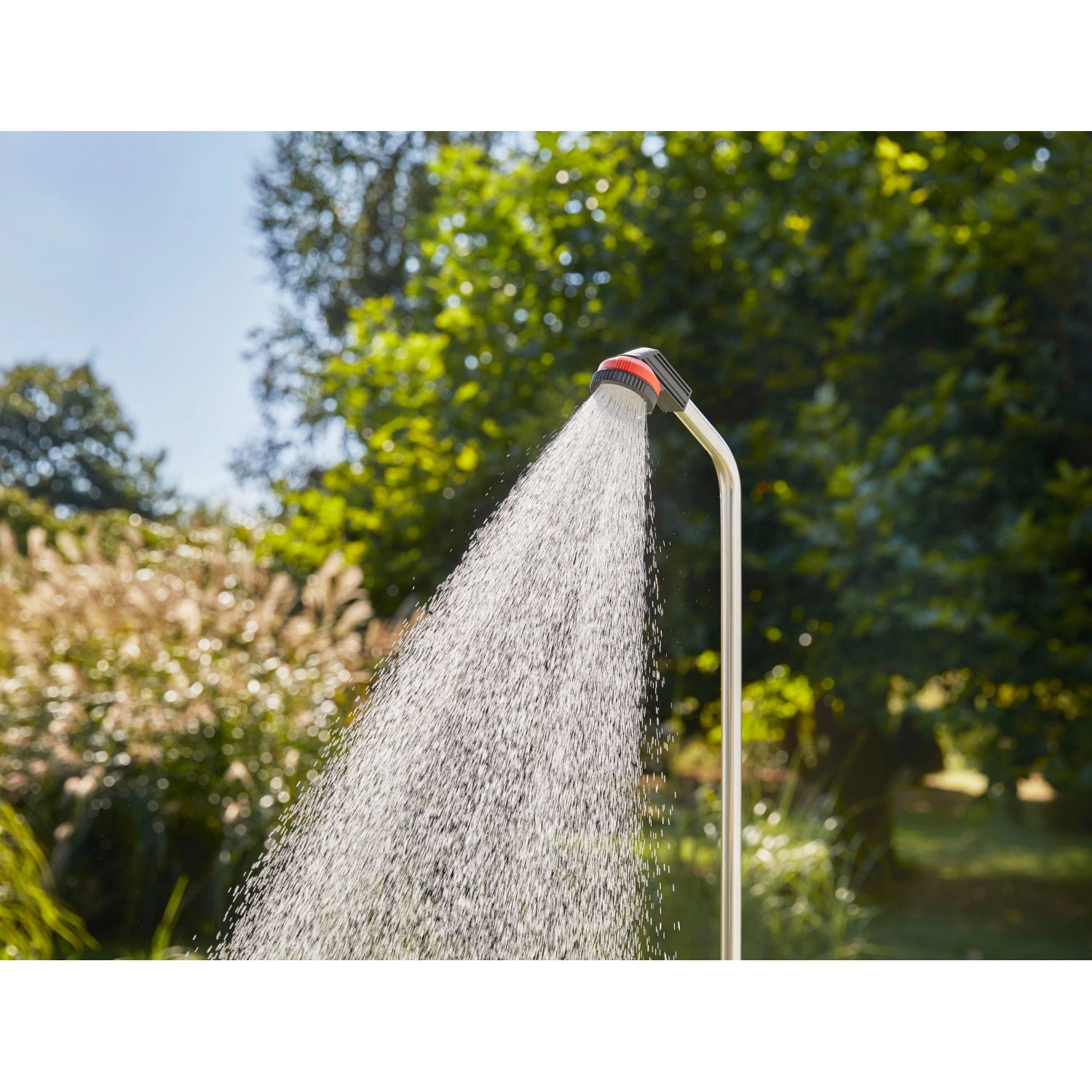 Gardena Gartendusche Solo im Einsatz: Wasserstrahl aus Duschkopf vor grünem Hintergrund.