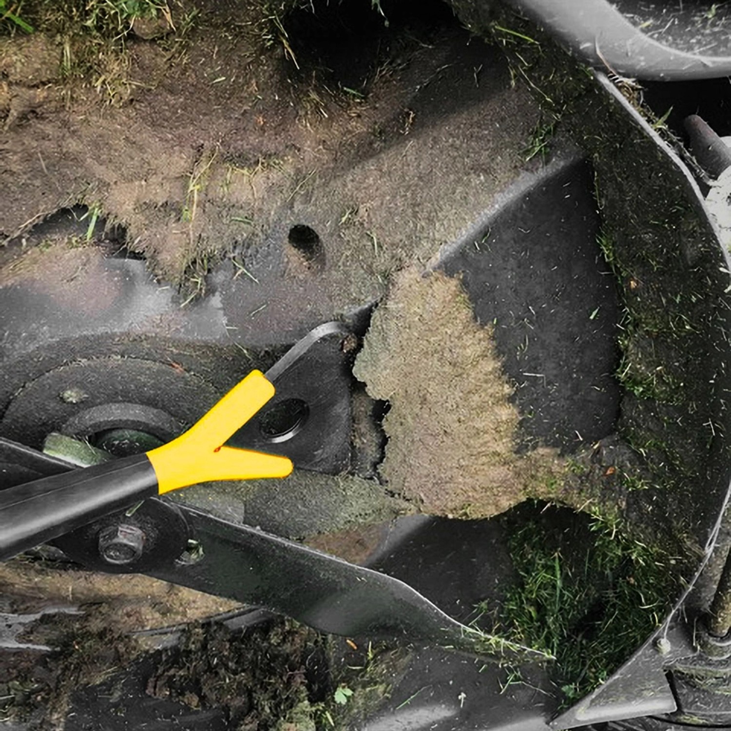 Texas Reinigungswerkzeug im Einsatz unter einem Mähroboter, um Grasreste zu entfernen.