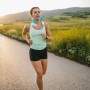 Frau joggt mit Livington Cool2Go Nackenkühler auf einer Landstraße.