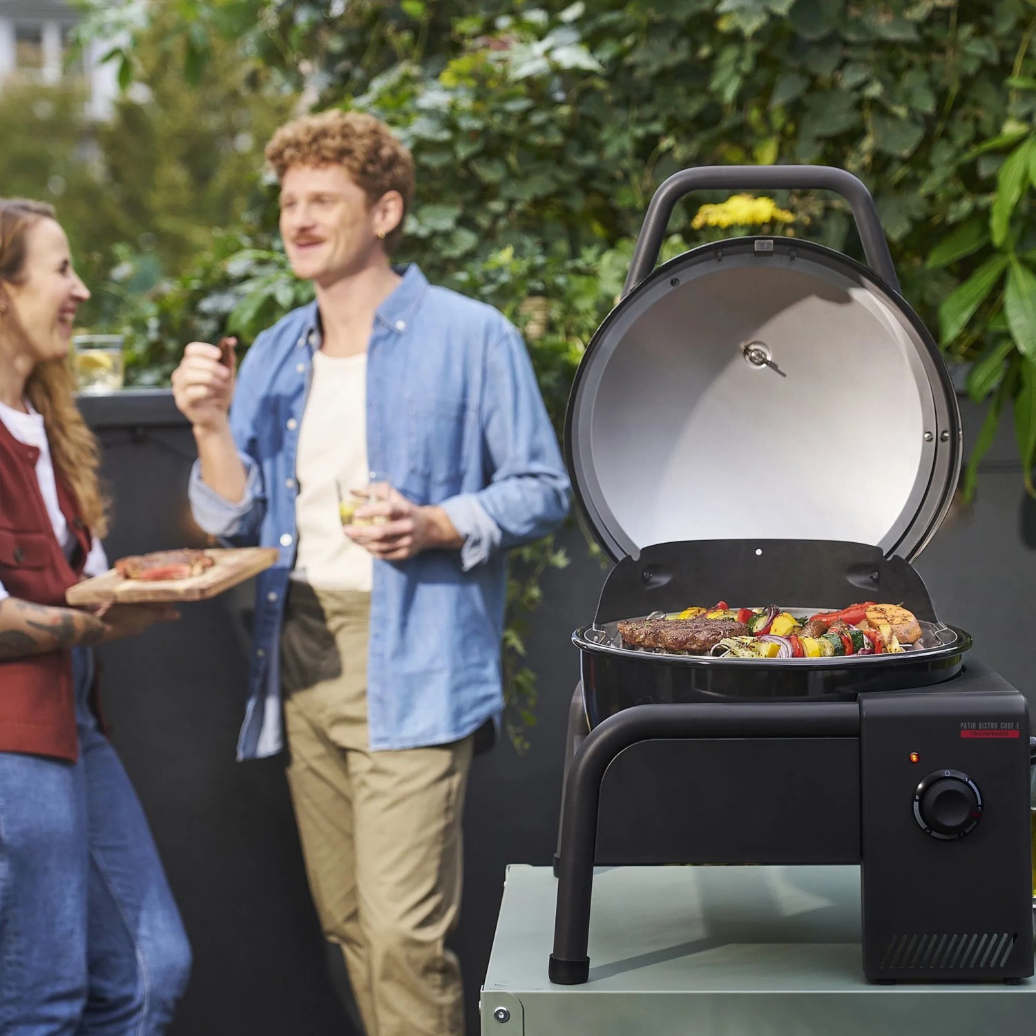 Schwarzer Char-Broil Elektrogrill Patio Bistro Cube E, geöffnet mit Grillgut. Mobil, ideal für Balkon & Terrasse.