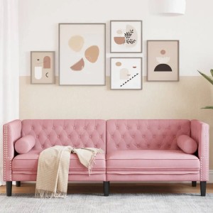 Rosa Chesterfield Sofa 3-Sitzer aus Samt mit Nackenrollen vor Wand mit Bildern.
