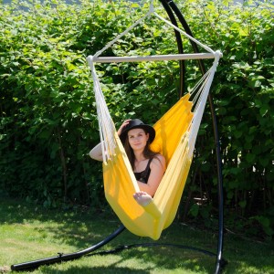 Gelber AMANKA Hängesessel mit Person im Garten. Bequemer Schwebesessel mit Holzstab und Metall Swivel.